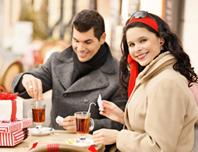 Mann und Frau stehen am Tisch und trinken Glühwein